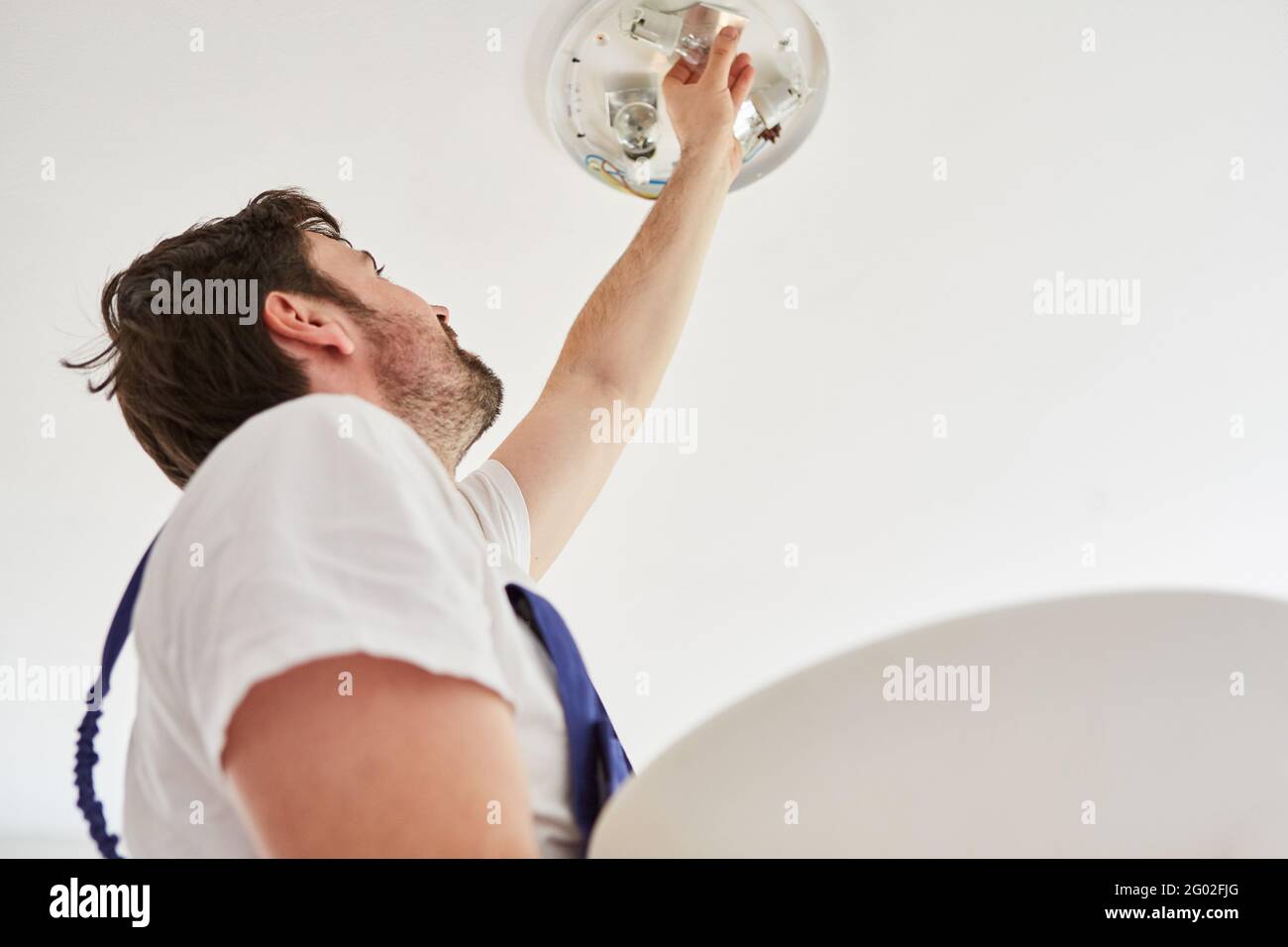 L'elettricista collega una lampada da soffitto con diverse luci a LED lampadine Foto Stock