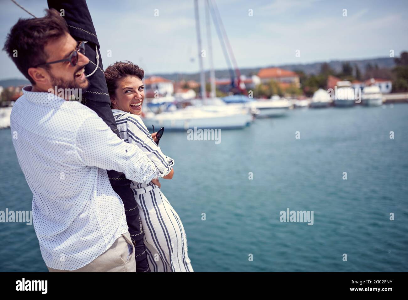 Un giovane couplein un abbraccio sta godendo sulla prua dello yacht insieme mentre cavalcano in una bella giornata di sole sul mare. Estate, mare, vacanza, relat Foto Stock