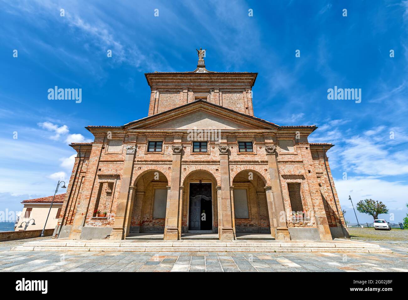 Vista ad angolo basso della vecchia chiesa cattolica in mattoni sotto il cielo blu nella piccola città di Diano d'Alba in Piemonte, Italia settentrionale. Foto Stock