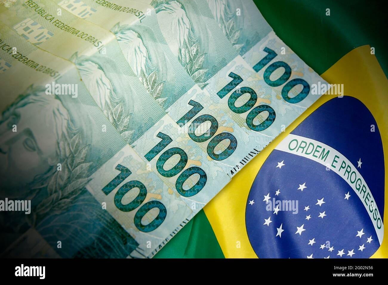 Primo piano di 100 banconote brasiliane reali davanti alla bandiera nazionale. Concetto di finanza e business Foto Stock