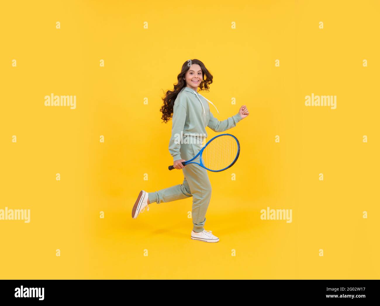 happy energico bambino salto in abbigliamento sportivo con racchetta da tennis in corsa al successo, infanzia attiva. Foto Stock