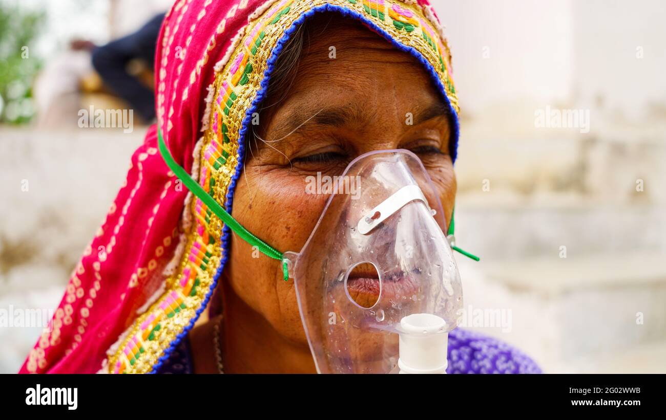 20 maggio 2021 - Reengus, Sikar, India. Vecchia donna indiana infettata con la malattia di Covid 19. Maschera per l'inalazione di ossigeno con flusso di ossigeno liquido. Foto Stock