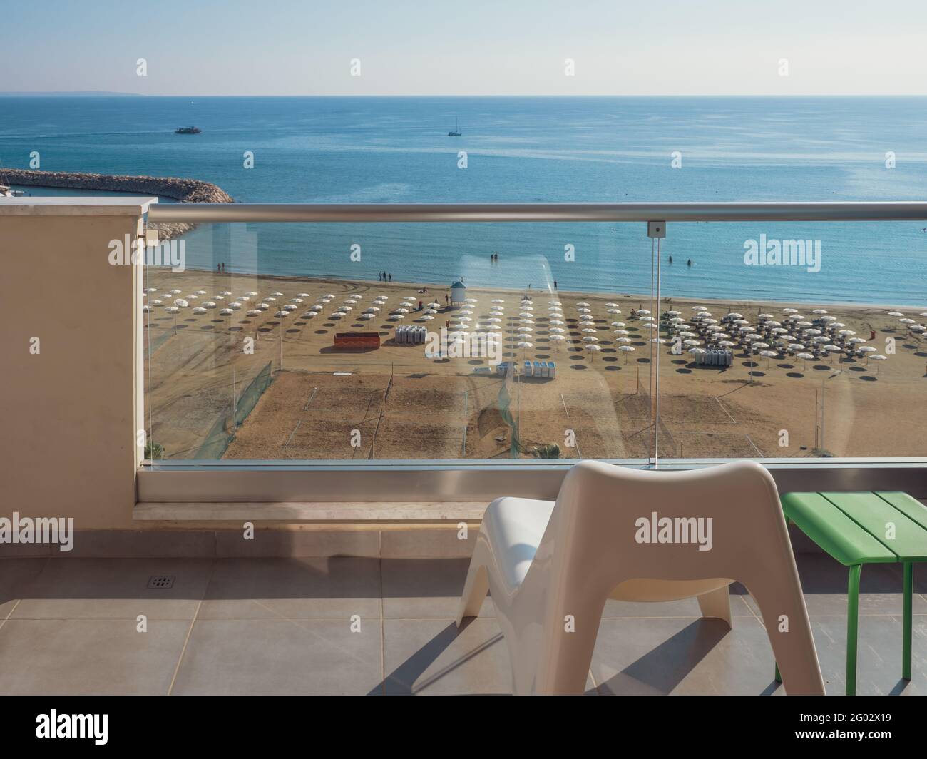 Vista panoramica sul mare Mediterraneo dal balcone con lettino in plastica,  tavolo verde e corrimano in vetro. Spiaggia con persone che riposano Foto  stock - Alamy