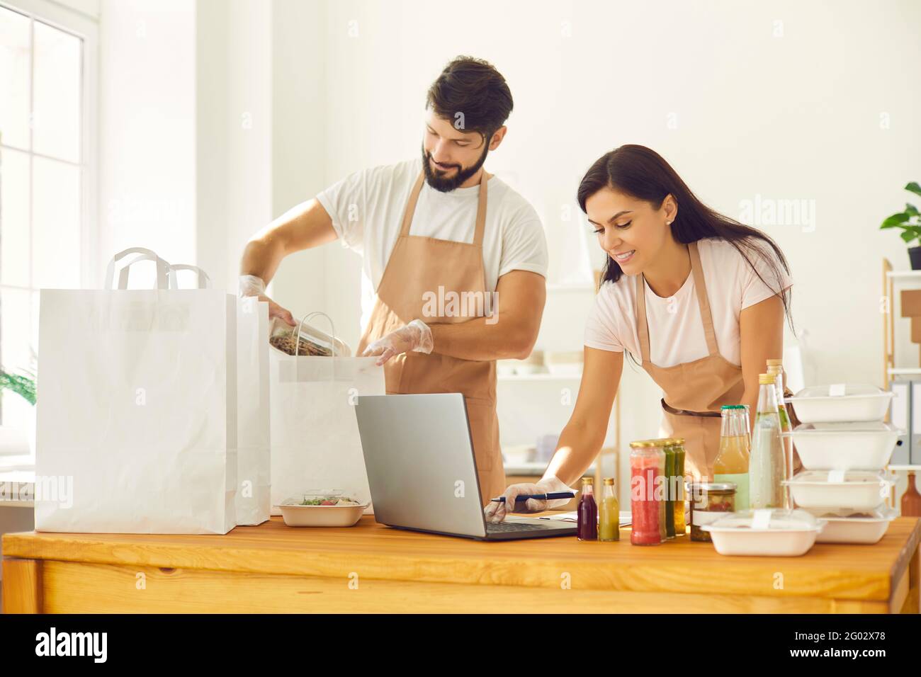 Due dipendenti di un bar da asporto stanno imballando contenitori di cibo per la consegna ai loro clienti. Foto Stock