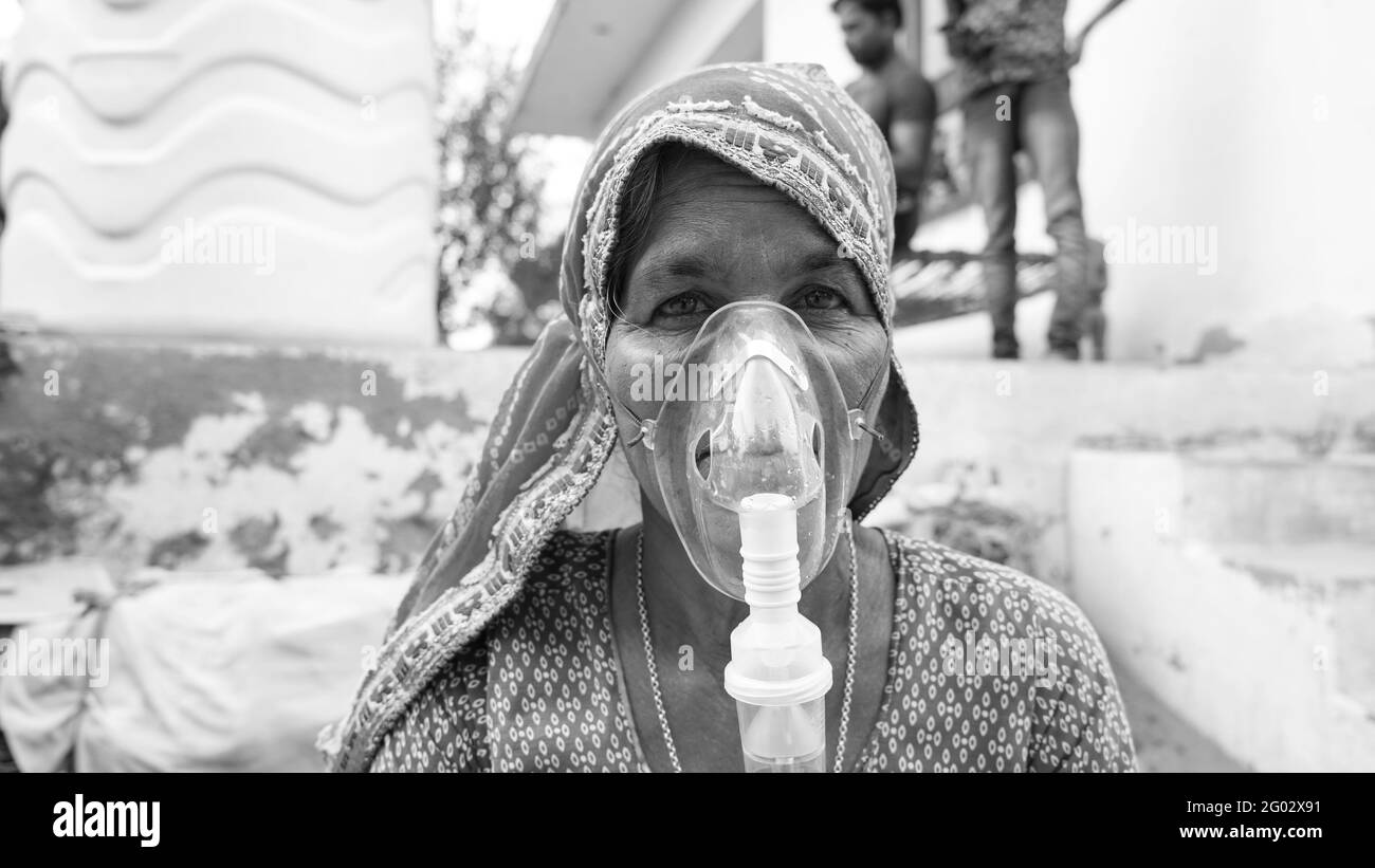 20 maggio 2021 - Reengus, Sikar, India. Vecchia donna indiana infettata con la malattia di Covid 19. Maschera per l'inalazione di ossigeno con flusso di ossigeno liquido. Foto Stock