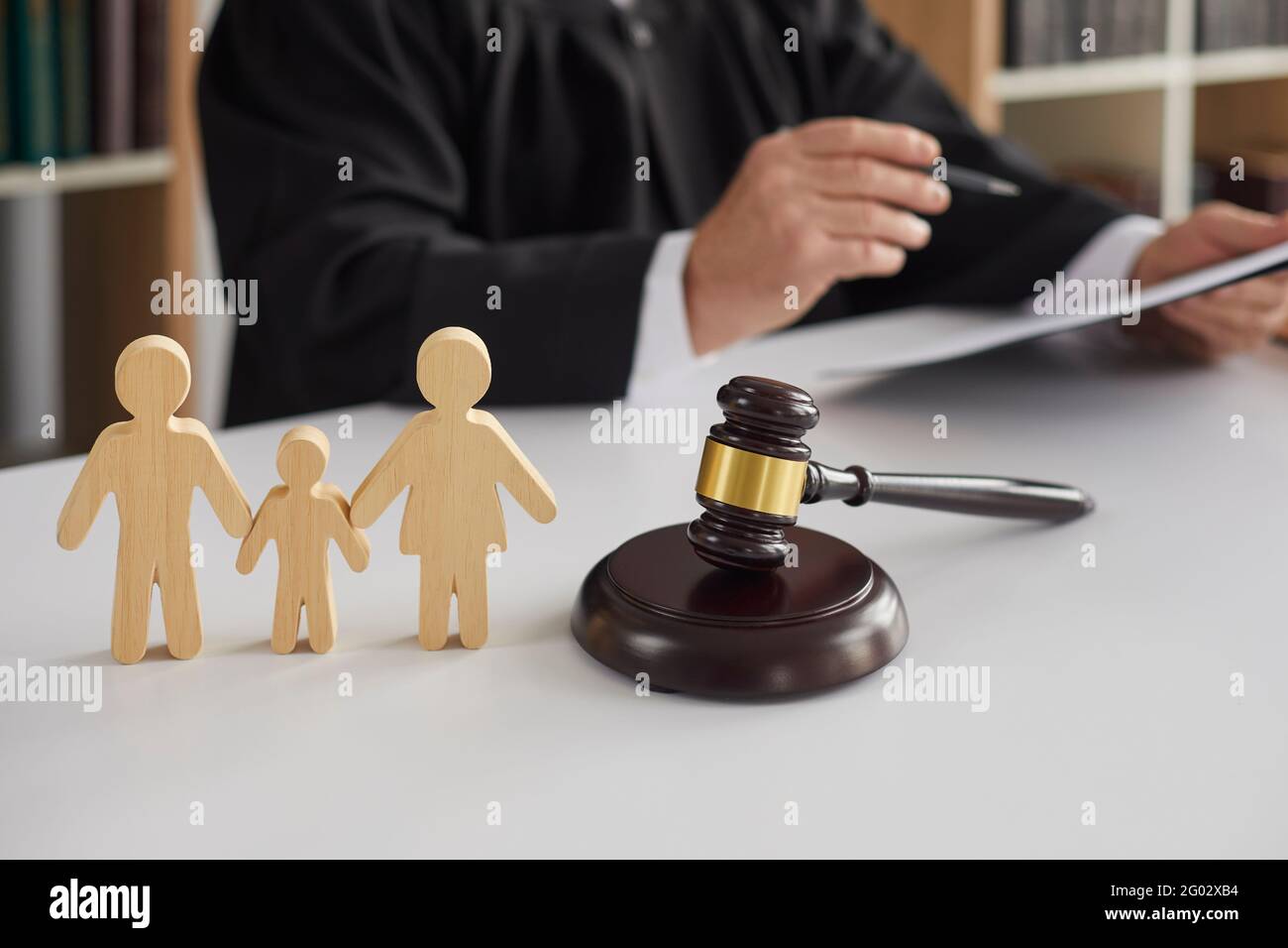 Figurine di legno di famiglia con bambino e gavel sullo sfondo del giudice che conduce il processo di divorzio. Foto Stock