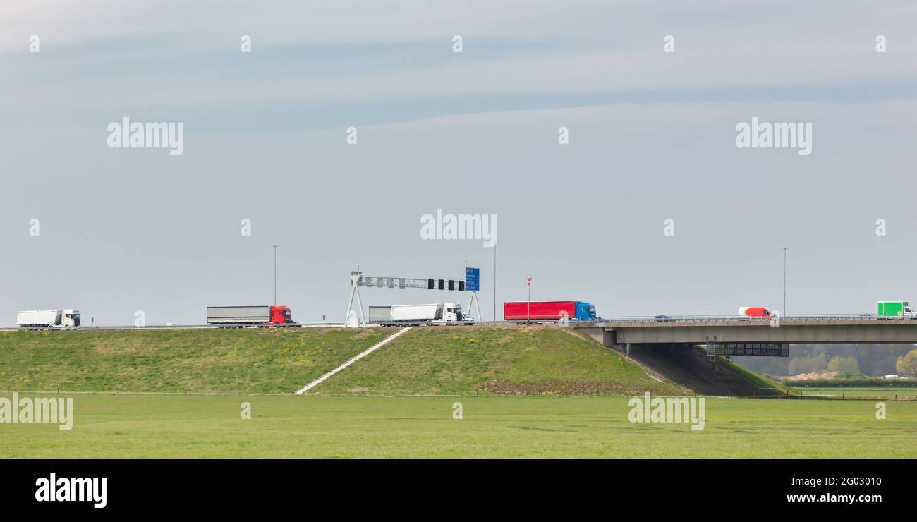 Fila di camion che trasportano il carico sull'autostrada olandese A1 a Deventer, Gelderland Foto Stock