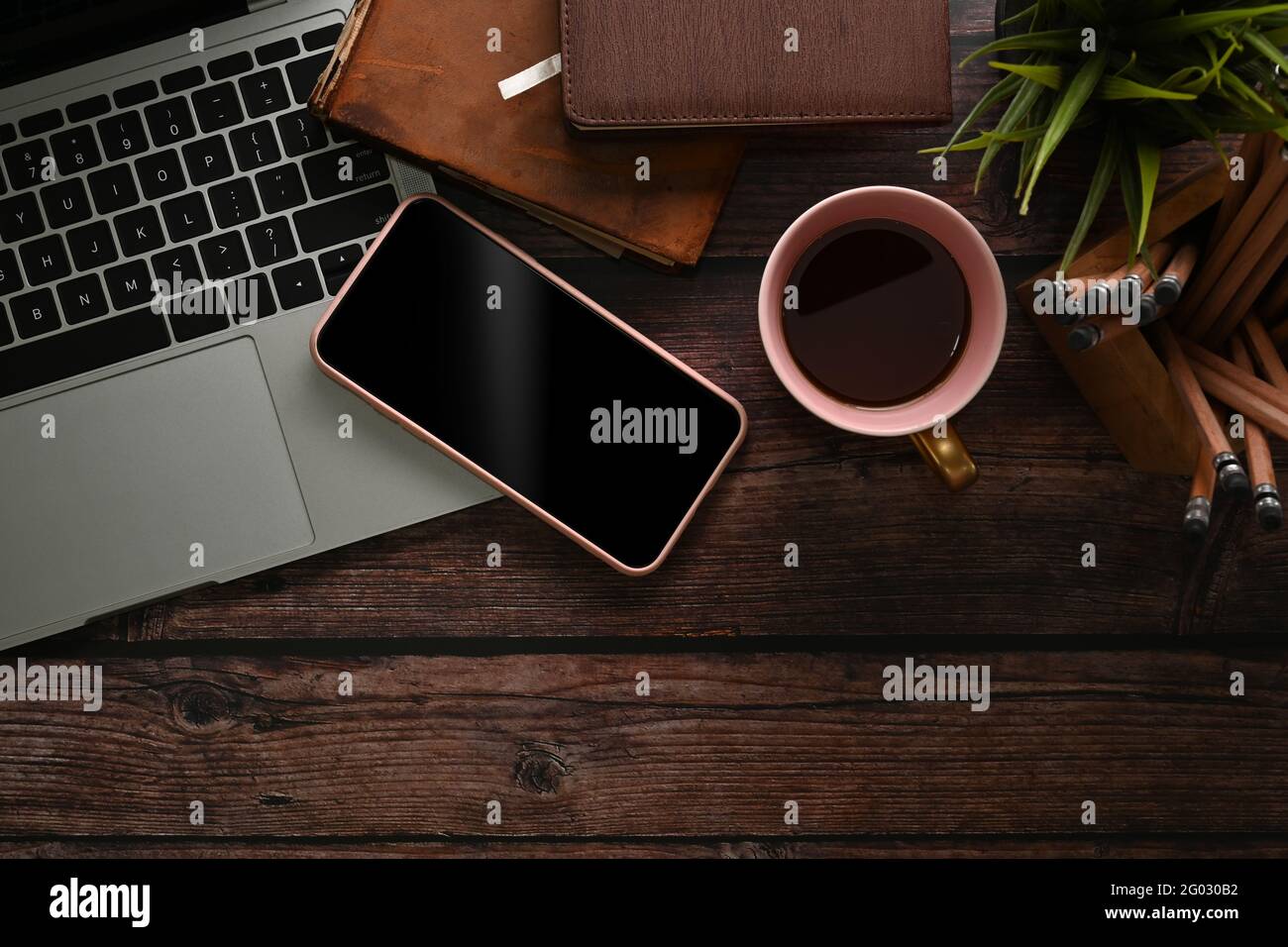 Area di lavoro sopra la vista con computer portatile, tazza da caffè, porta matita e cono mobile. Foto Stock