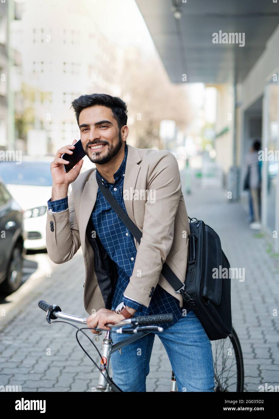 Un giovane uomo d'affari che lavora all'aperto in città e lavora con una bicicletta e uno smartphone. Foto Stock