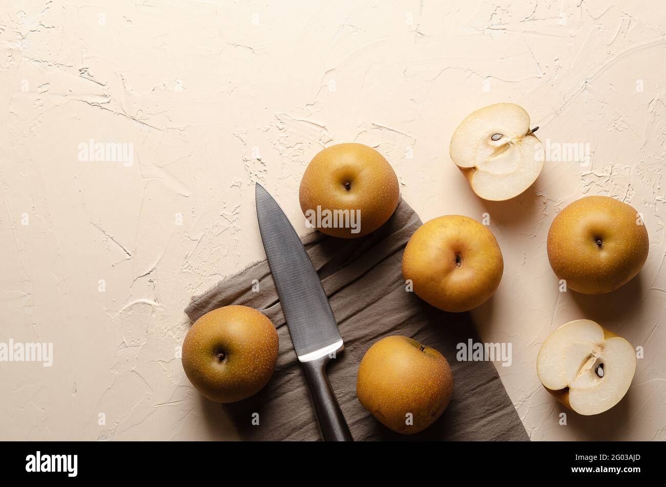 Pere asiatiche con un coltello d'argento su uno sfondo chiaro. Foto Stock