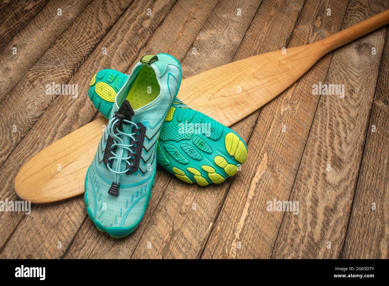 scarpe da ginnastica e una lama di pagaia in legno (coda di beaver) contro sfondo di legno intemperato Foto Stock