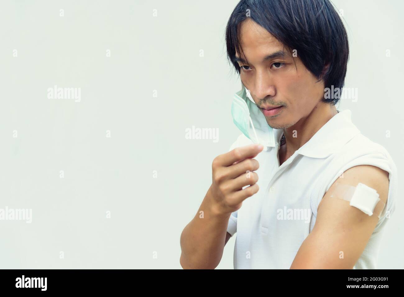 uomo asiatico rimuovere la maschera dopo essere stato vaccinato di covid-19 Foto Stock