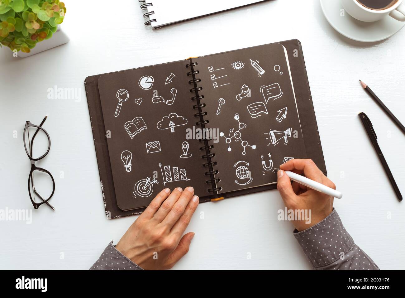Concetto di simboli di marketing digitale. Donna di affari designer mani disegnare note in notebook. Foto Stock