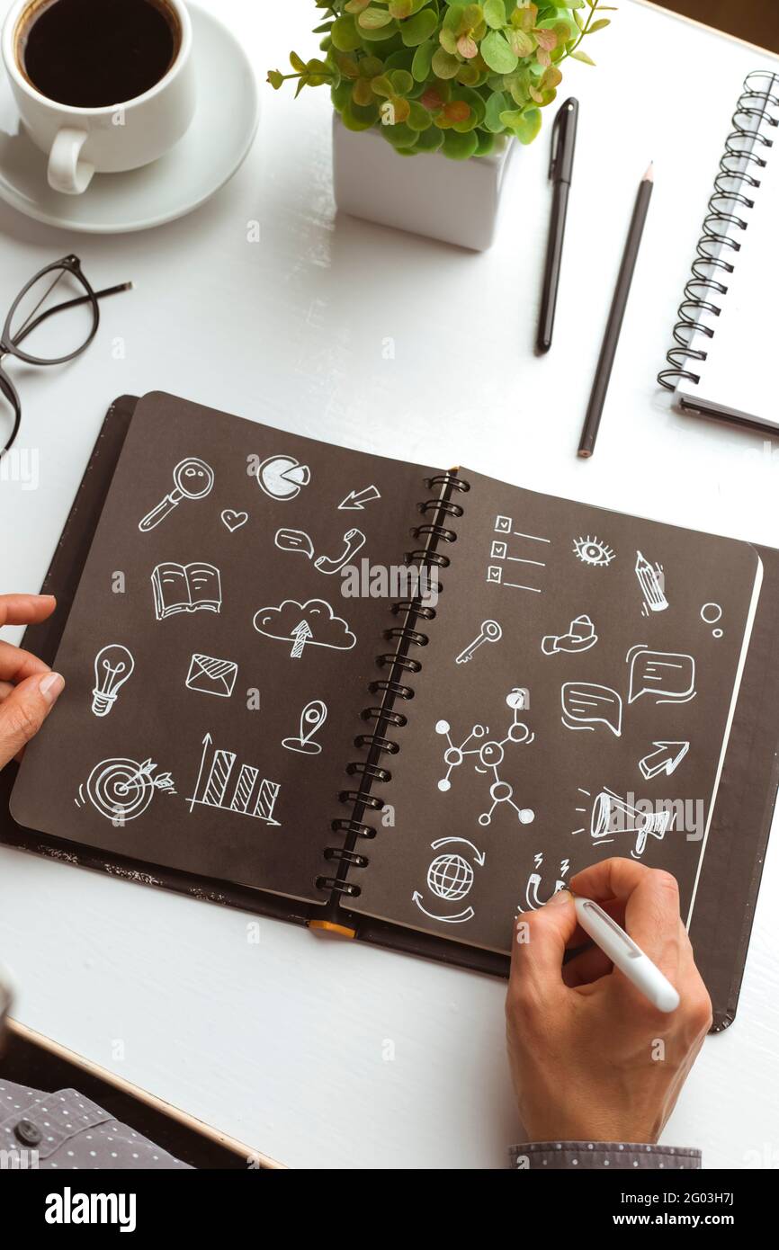 Concetto di simboli di marketing digitale. Donna di affari designer mani disegnare note in notebook. Foto Stock