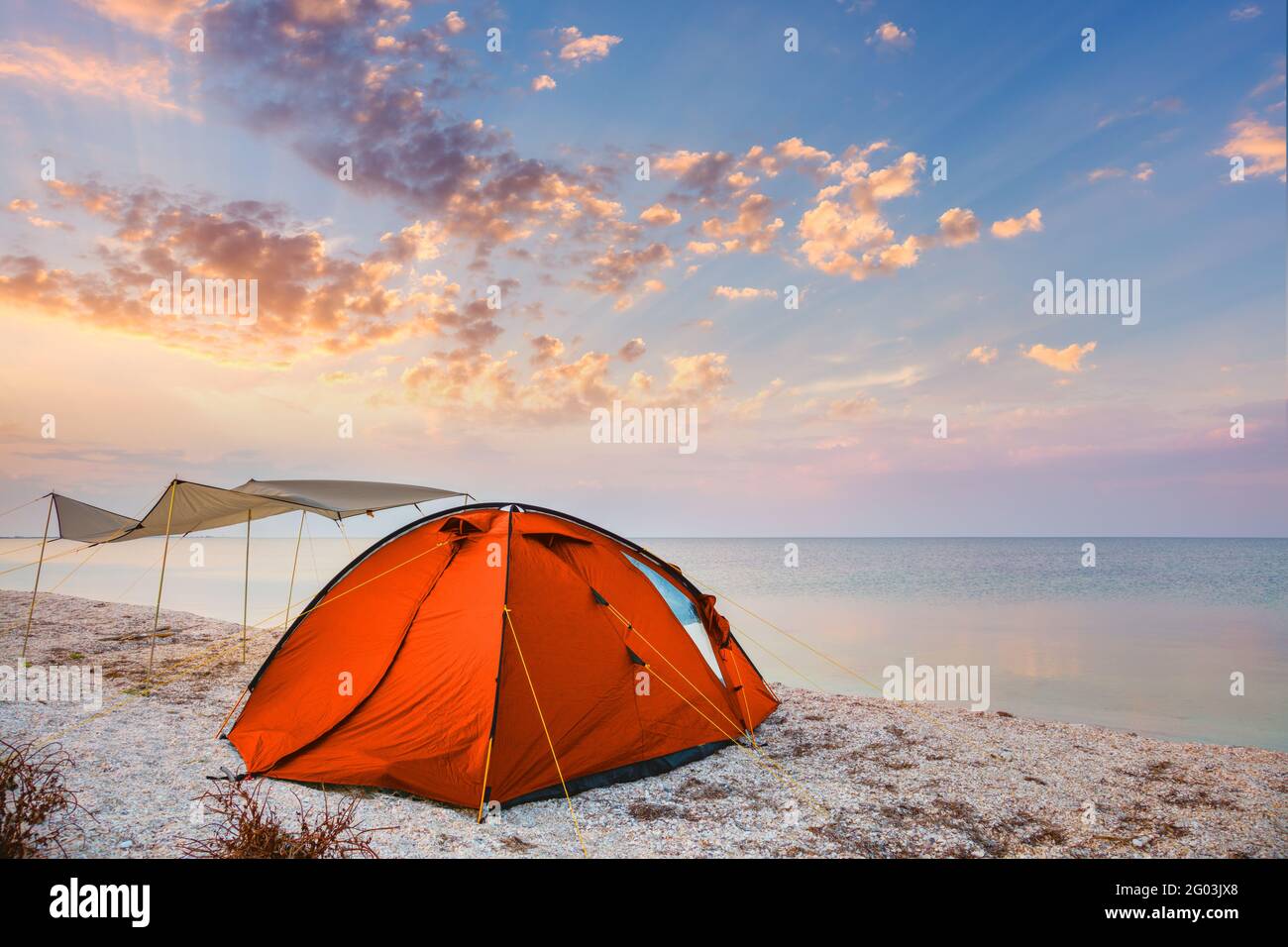 Campeggio tenda su una bella spiaggia tranquilla vicino all'acqua contro il tramonto cielo sfondo, felice estate tempo Foto Stock