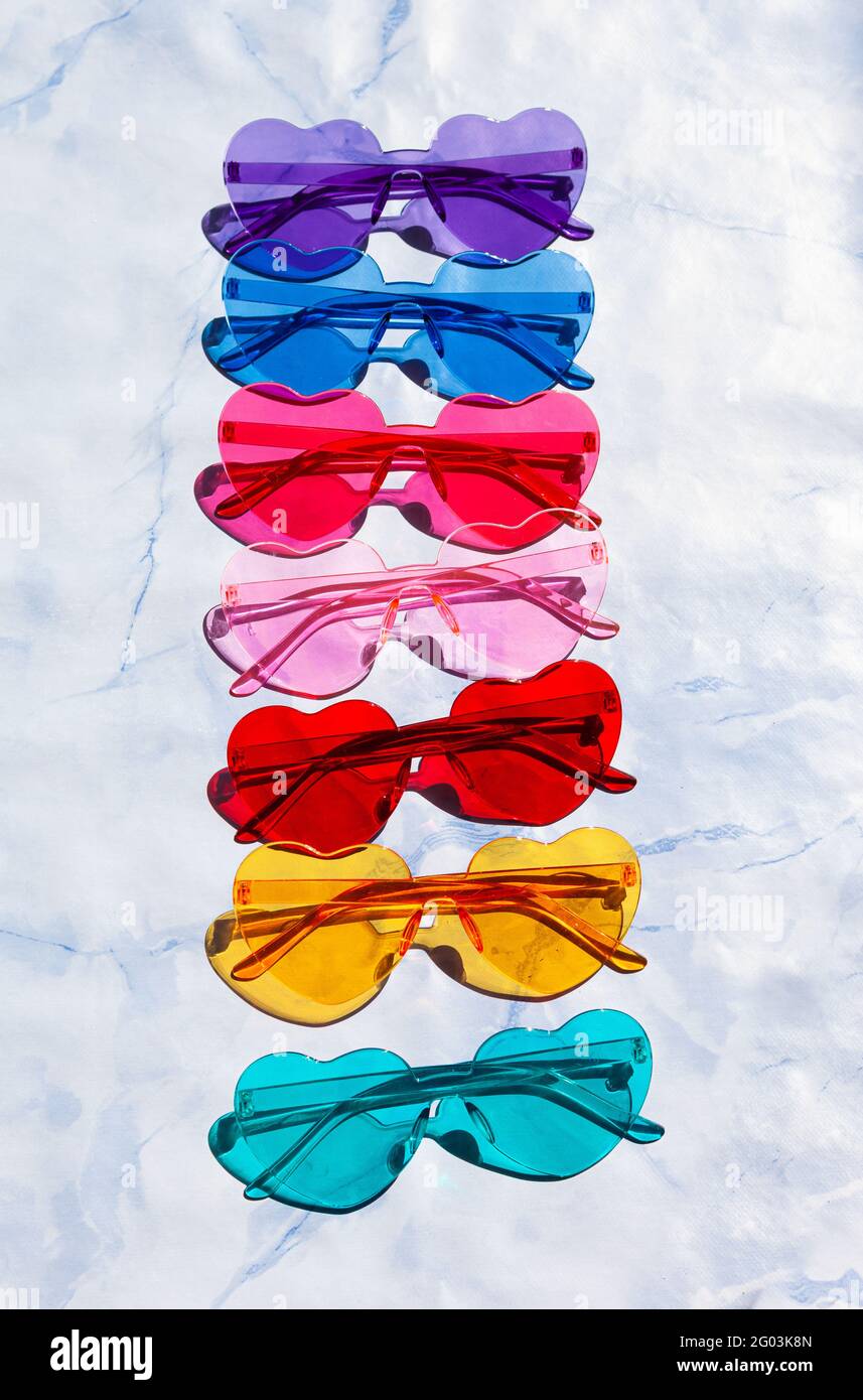 Occhiali da sole colorati a forma di cuore su sfondo blu Foto Stock