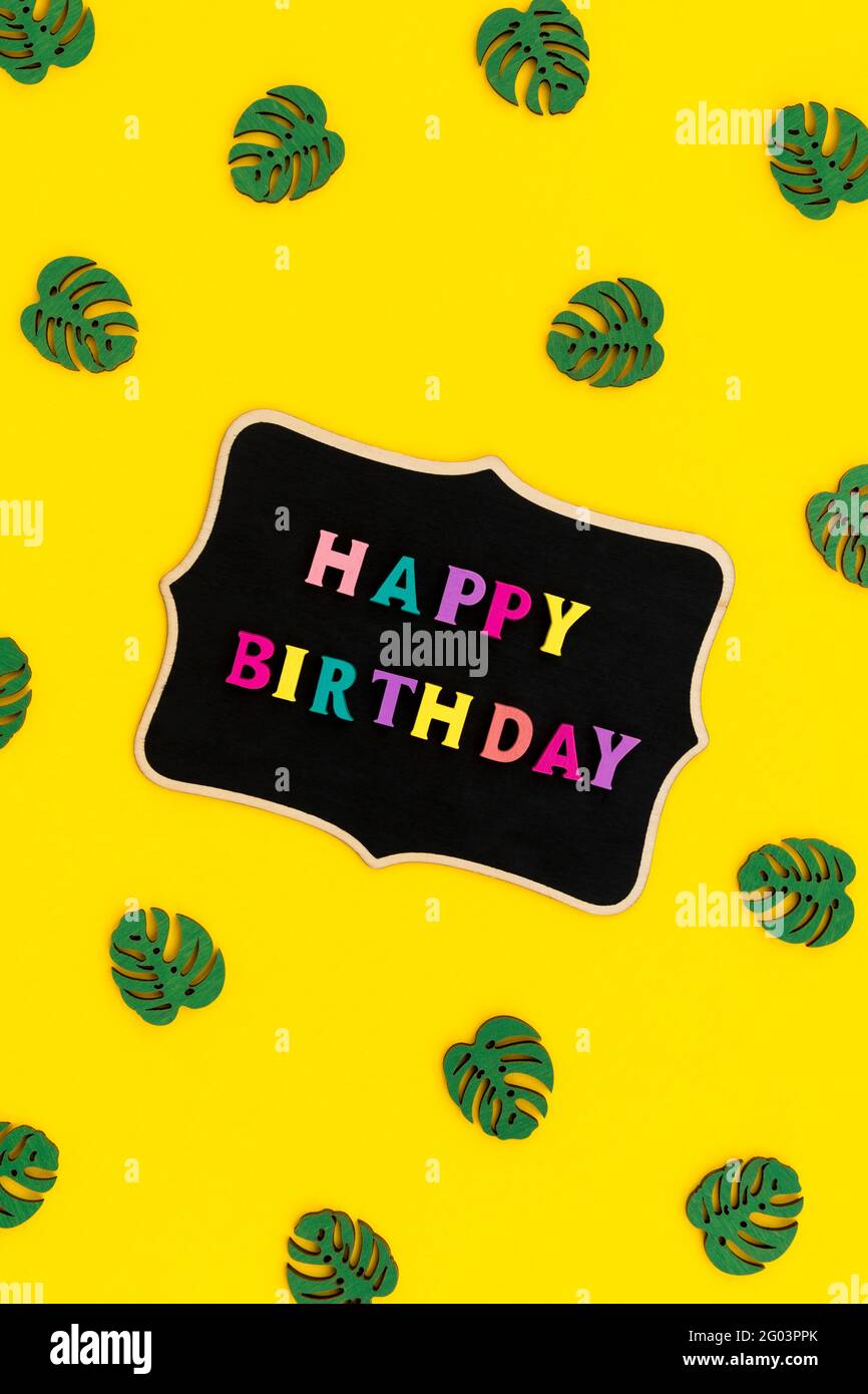 Felice iscrizione di compleanno da lettere colorate su tavola di legno Foto Stock