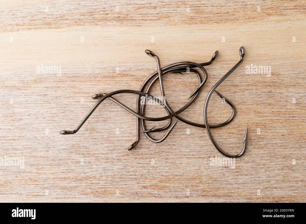 Vista dall'alto di un nuovo gancio di pesce a goccia su una superficie di legno. Foto Stock