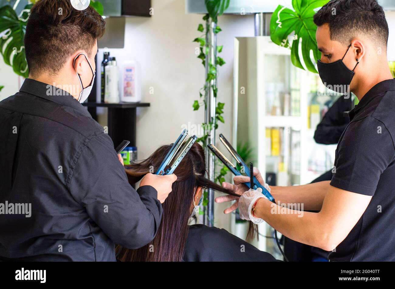 Ritratto di due giovani in parrucchiere che lavorano con forbici con camicia nera. Foto Stock