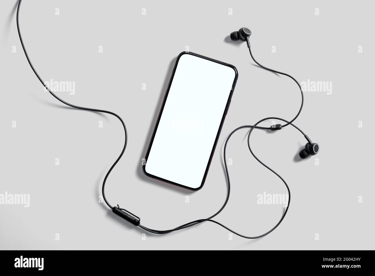 Mockup per smartphone con schermo bianco vuoto per annunci o dimostrazioni di applicazioni mobili alla moda. Cuffie, sfondo grigio. Applicazione per i social media Foto Stock