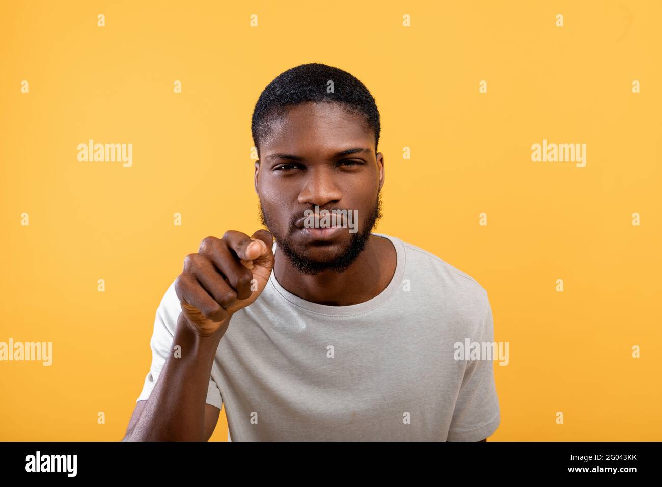Concetto di sospetto. Uomo afro-americano che guarda e punta il dito verso la telecamera, standig su sfondo giallo Foto Stock