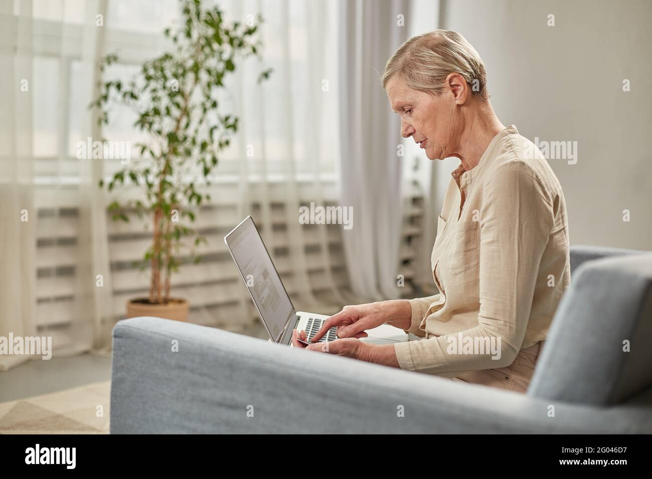 Una donna anziana paga per un prodotto o un servizio vicino mezzo di una carta di credito su un computer Foto Stock