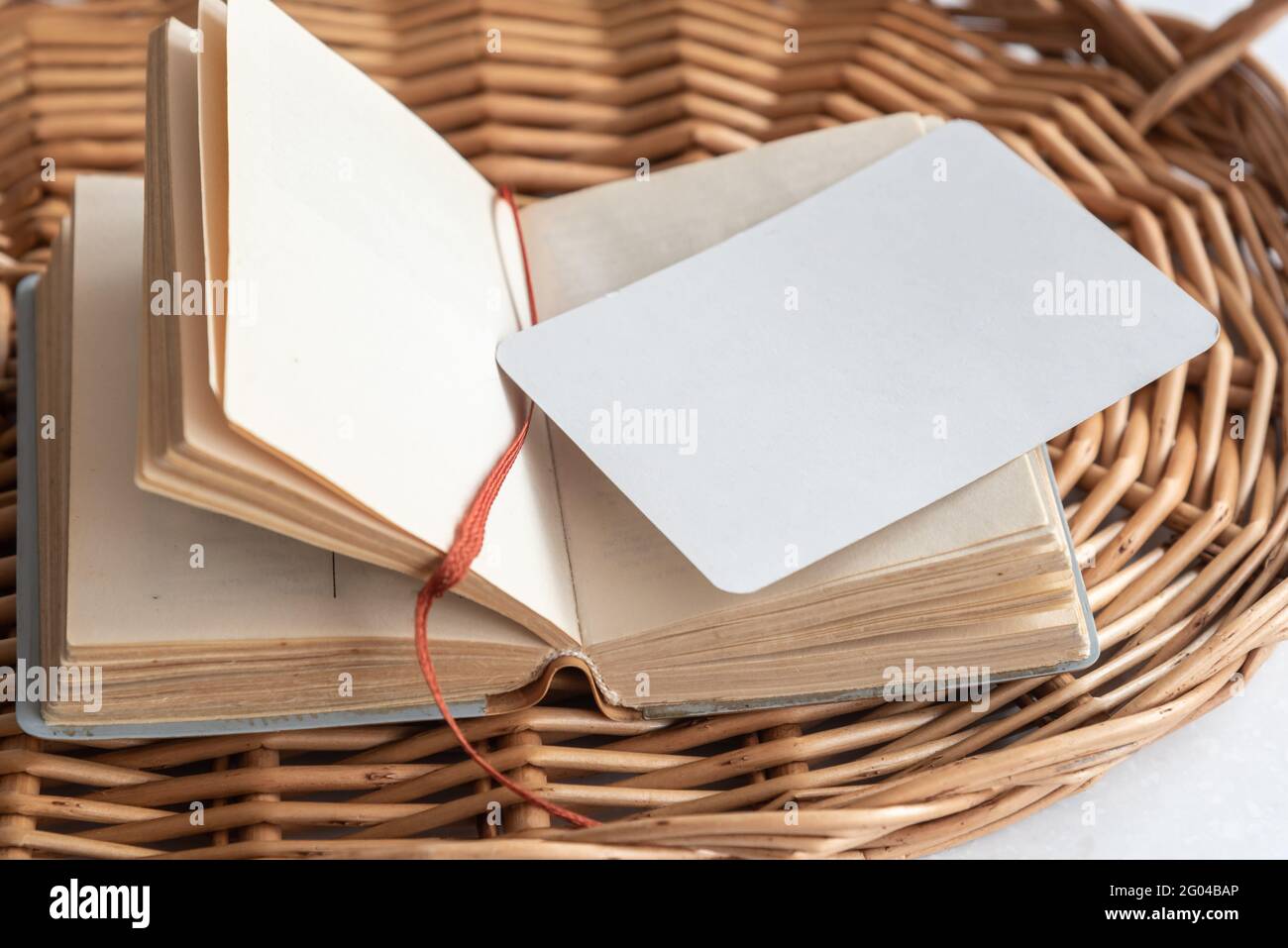 Biglietto da visita vuoto su un notebook di carta aperto sul vassoio di vimini Foto Stock