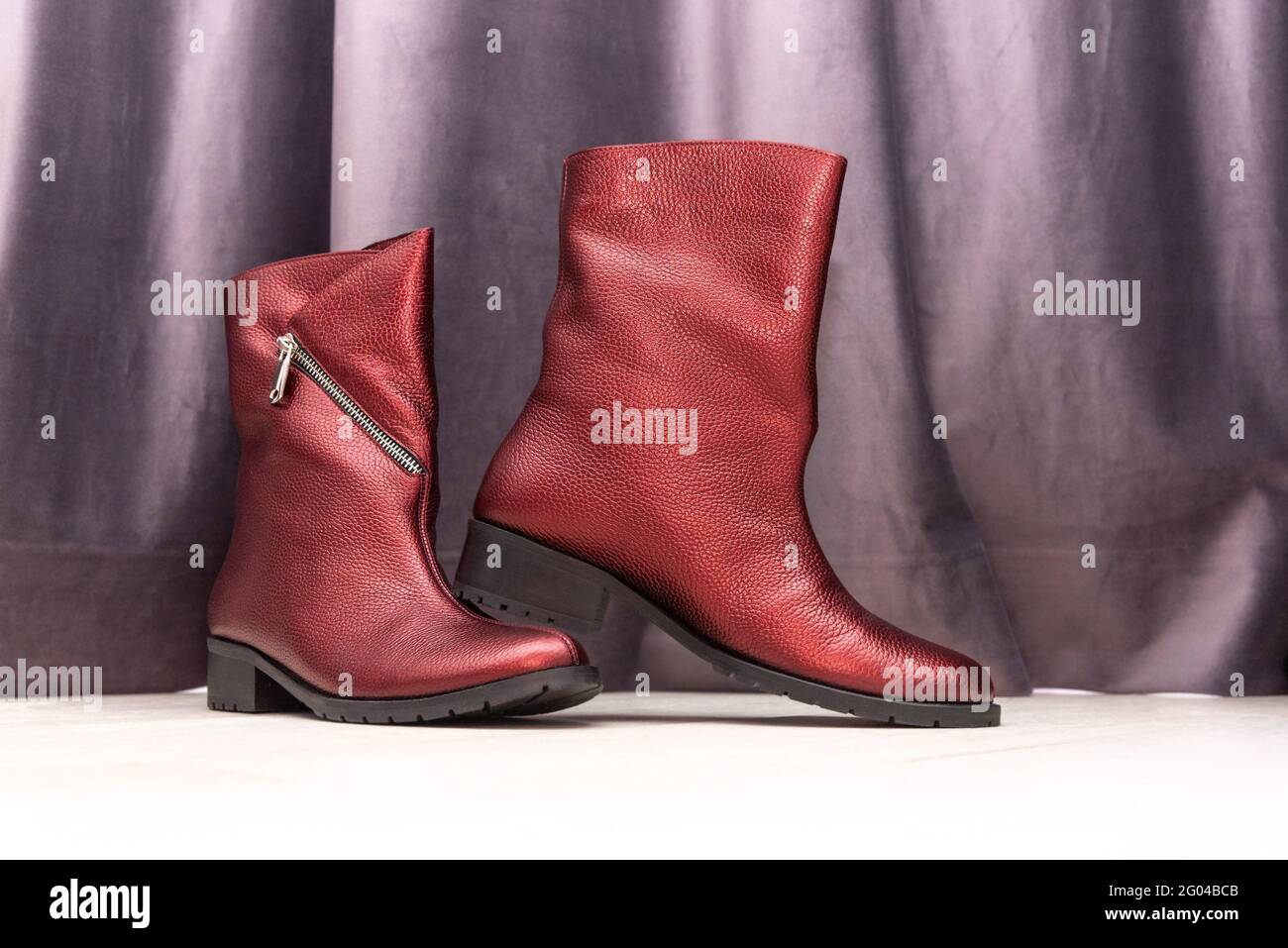 Stivali da donna rossi con tacchi bassi vicino alla tenda viola camera Foto Stock