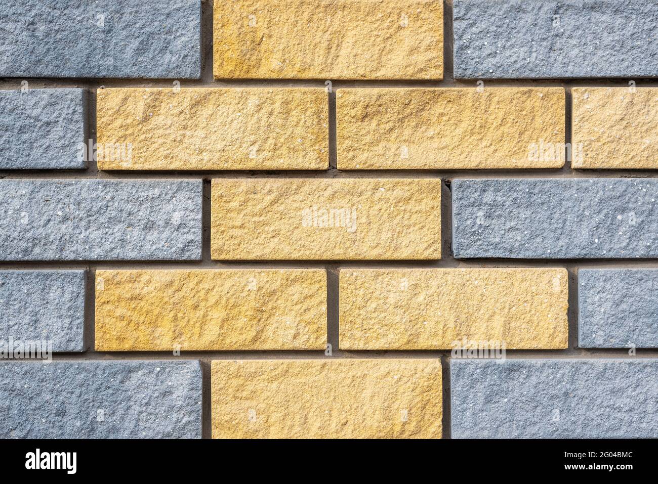 Parete di blocchi di pietra di colore grigio chiaro e giallo Foto Stock