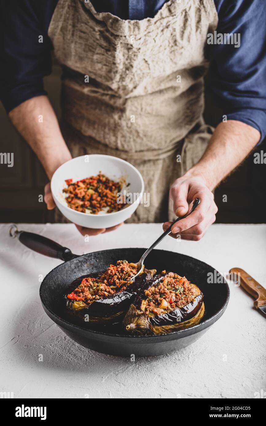 Preparazione delle melanzane farcite con carne macinata, pomodori e spezie. Piatto tradizionale Karniyarik di cucina turca Foto Stock