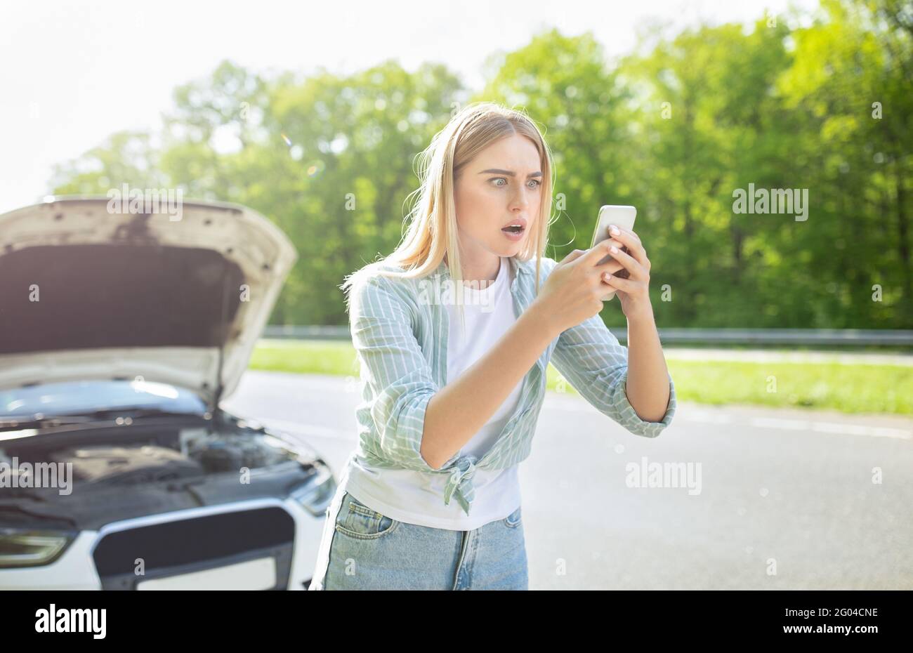 Terrorizzata donna bionda in cerca di segnale dopo un'avaria dell'auto, in possesso di smartphone, non riesce a trovare la rete mobile Foto Stock