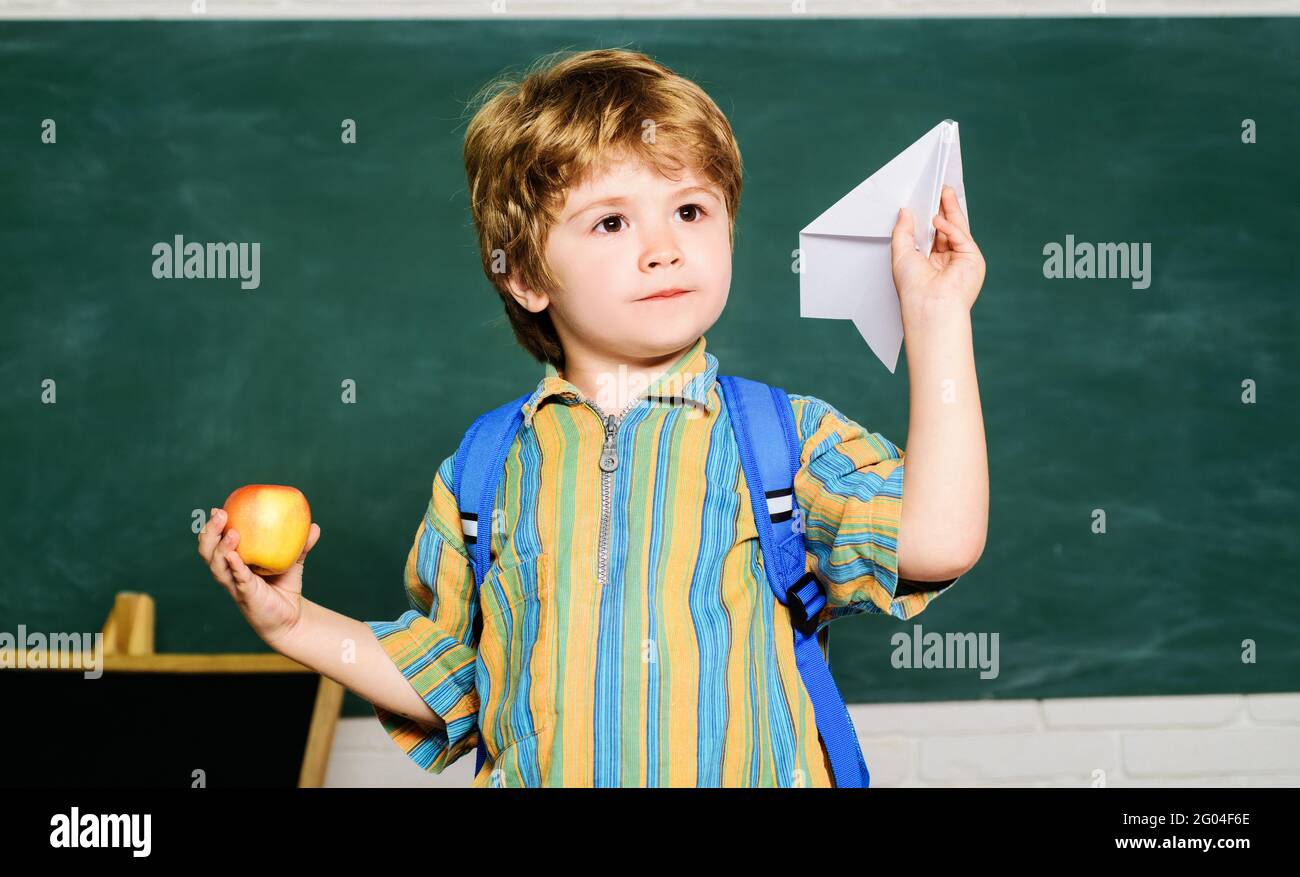 Bambino con aereo origami in scuola primaria. Il ragazzo piccolo gioca con l'aereo di carta. Ritorno a scuola e tempo felice. Foto Stock