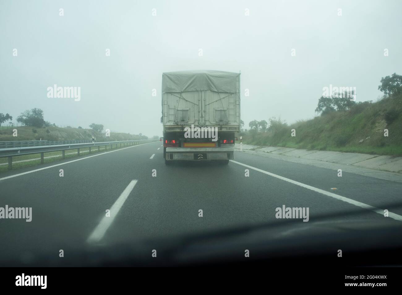 Guida dietro un carrello sotto nebbia fitta. Concetto di guida in caso di cattive condizioni atmosferiche Foto Stock