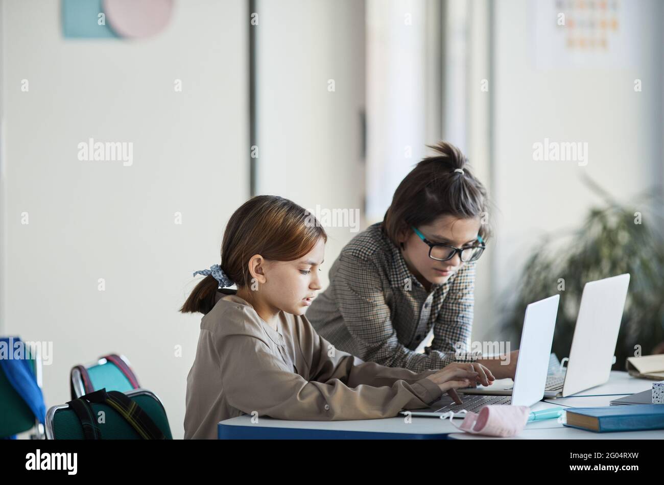 Vista laterale ritratto di due bambini utilizzando computer in interni scuola minimale, spazio di copia Foto Stock