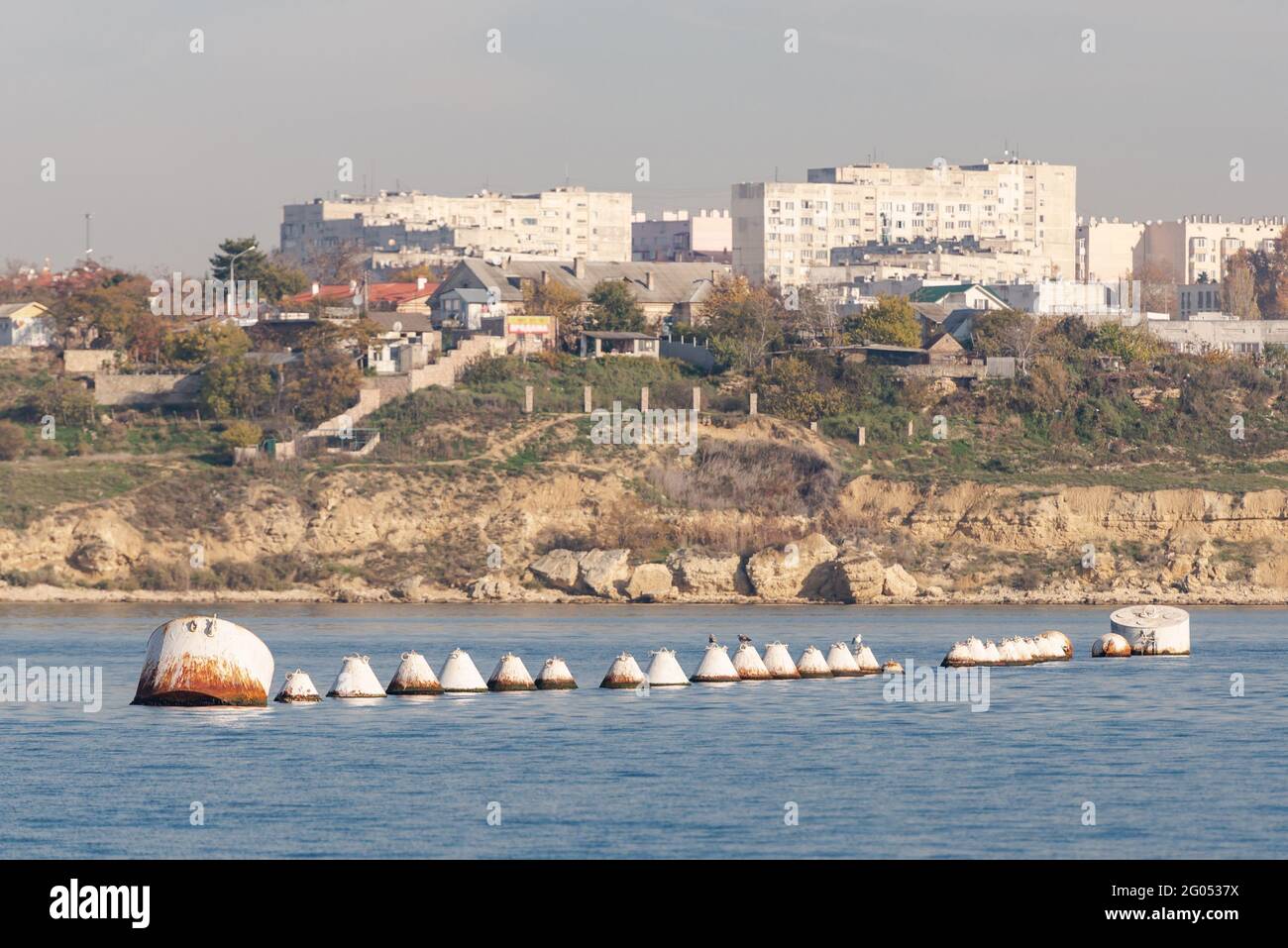 Una fila di grandi barili di ferro per ormeggiare le navi. Boe sullo sfondo della città di Sevastopol all'interno della baia. Foto Stock