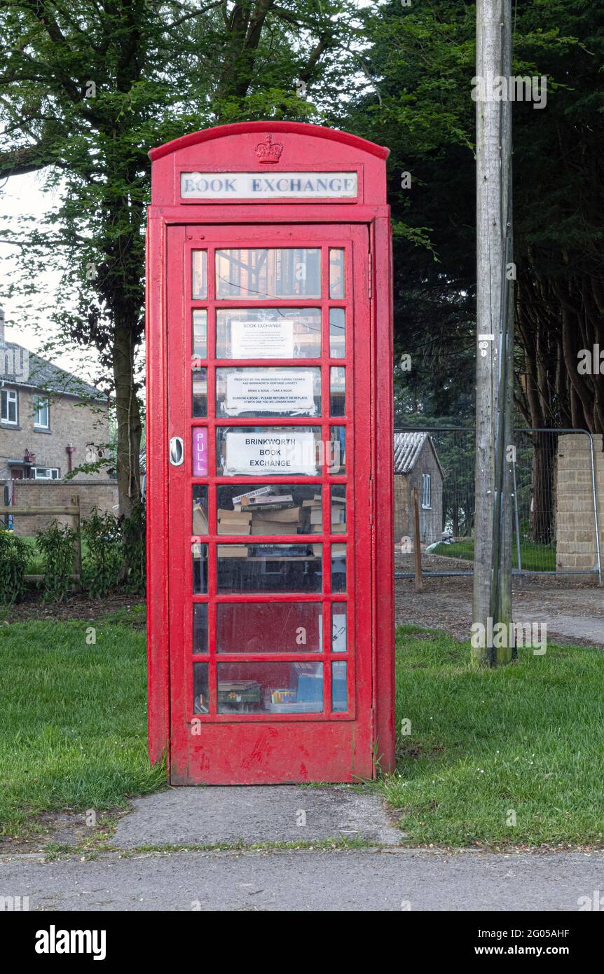 Vecchia scatola telefonica rossa usata come libro del villaggio di Brinkworth scambio Foto Stock