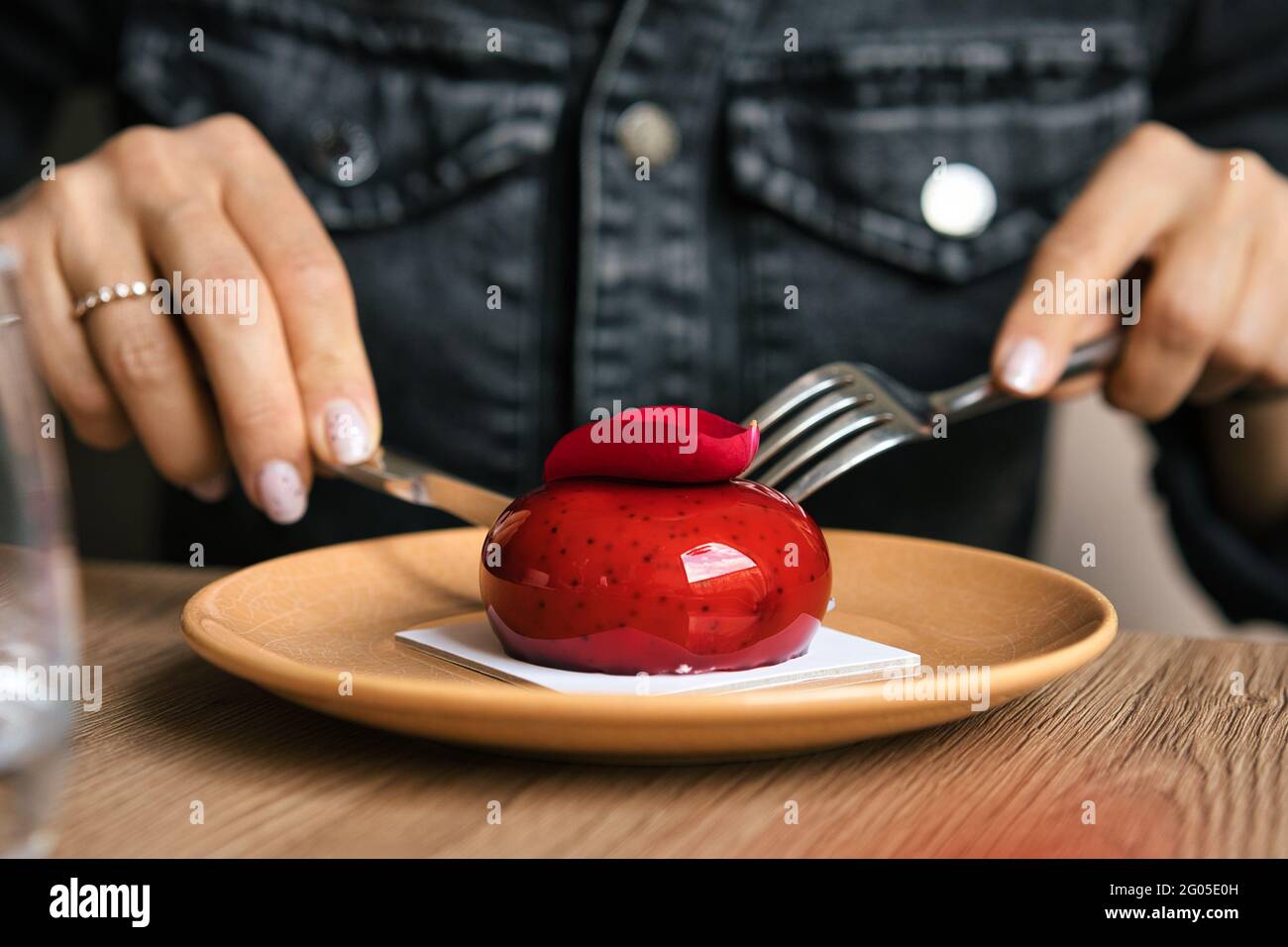 Torta di mousse francese ricoperta di smalto rosso su sfondo di legno. Pasticceria europea moderna. Messa a fuoco superficiale Foto Stock