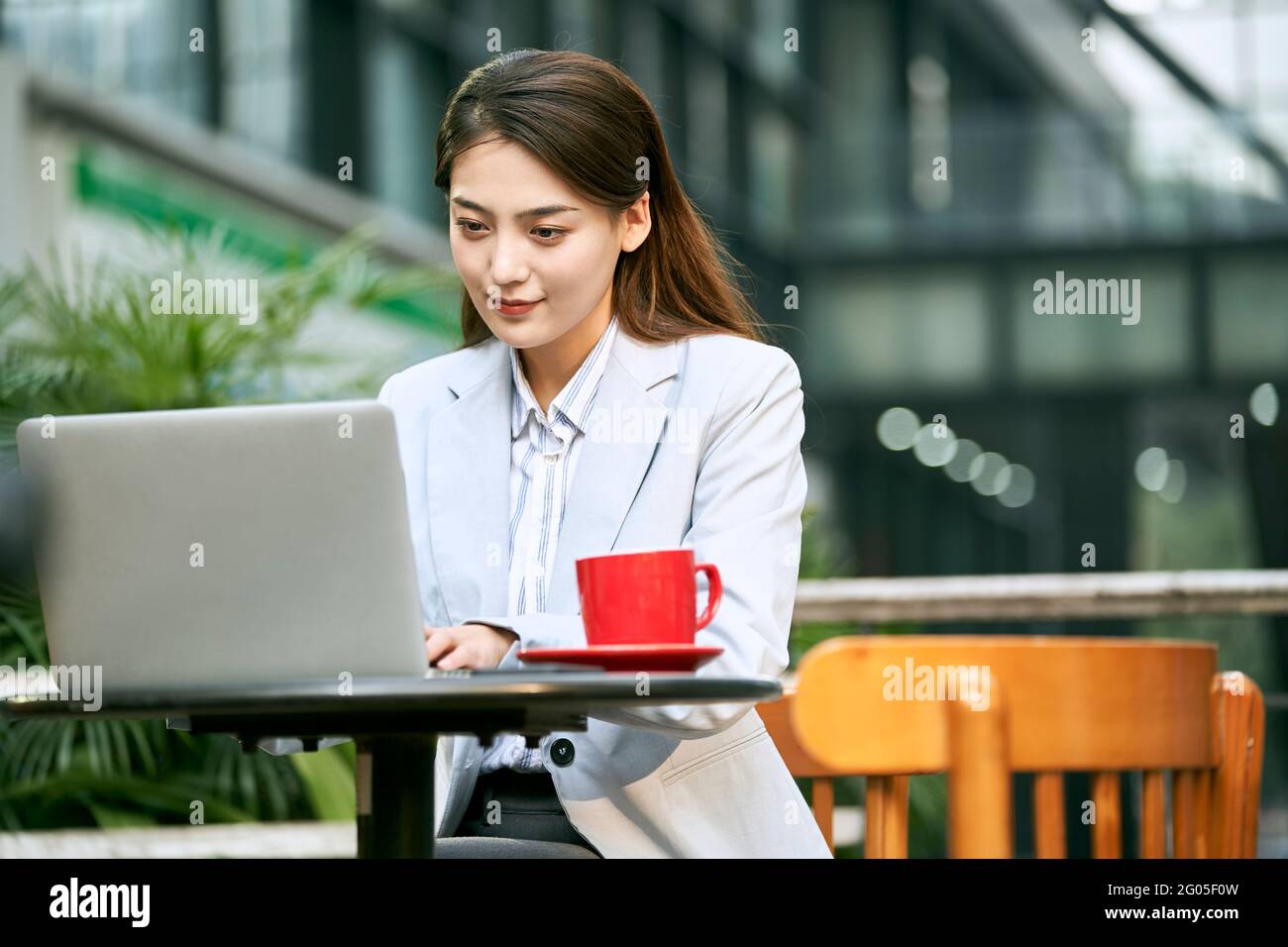 giovane donna d'affari asiatica che lavora all'aperto in una caffetteria utilizzando un computer portatile computer Foto Stock