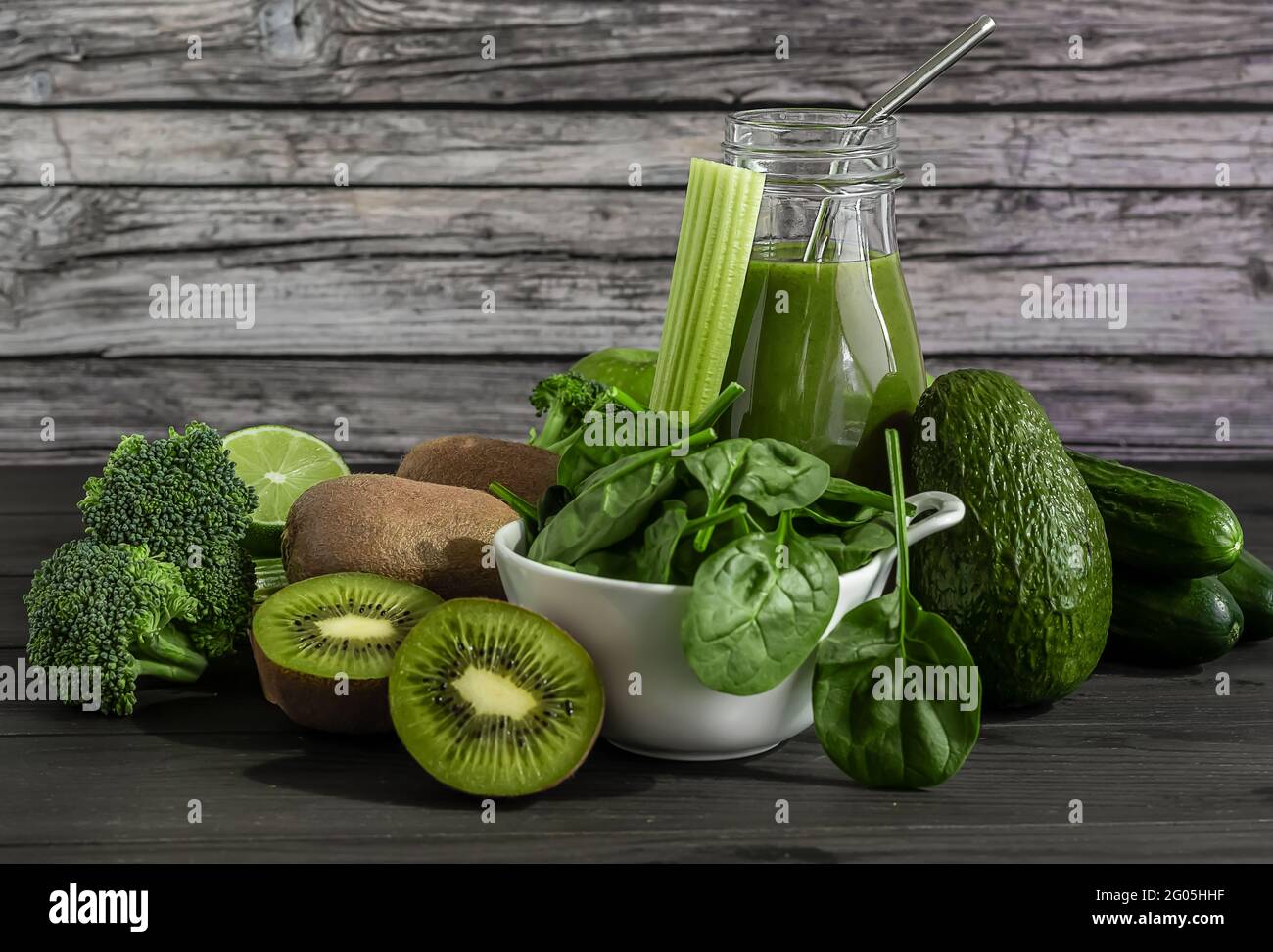 Frullato verde organico fresco con spinaci, cetrioli, kiwi, sedano e avocado su sfondo di legno. Foto Stock