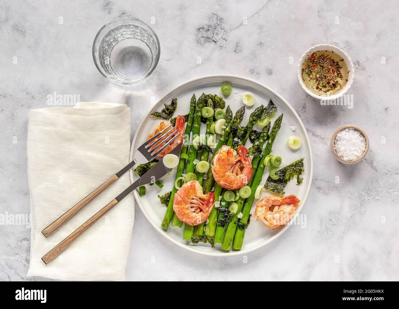 Deliziosa insalata sana di asparagi verdi, gamberi, cipolla e nori sul piatto bianco. Mangiare pulito. Cibo di stagione. Foto Stock