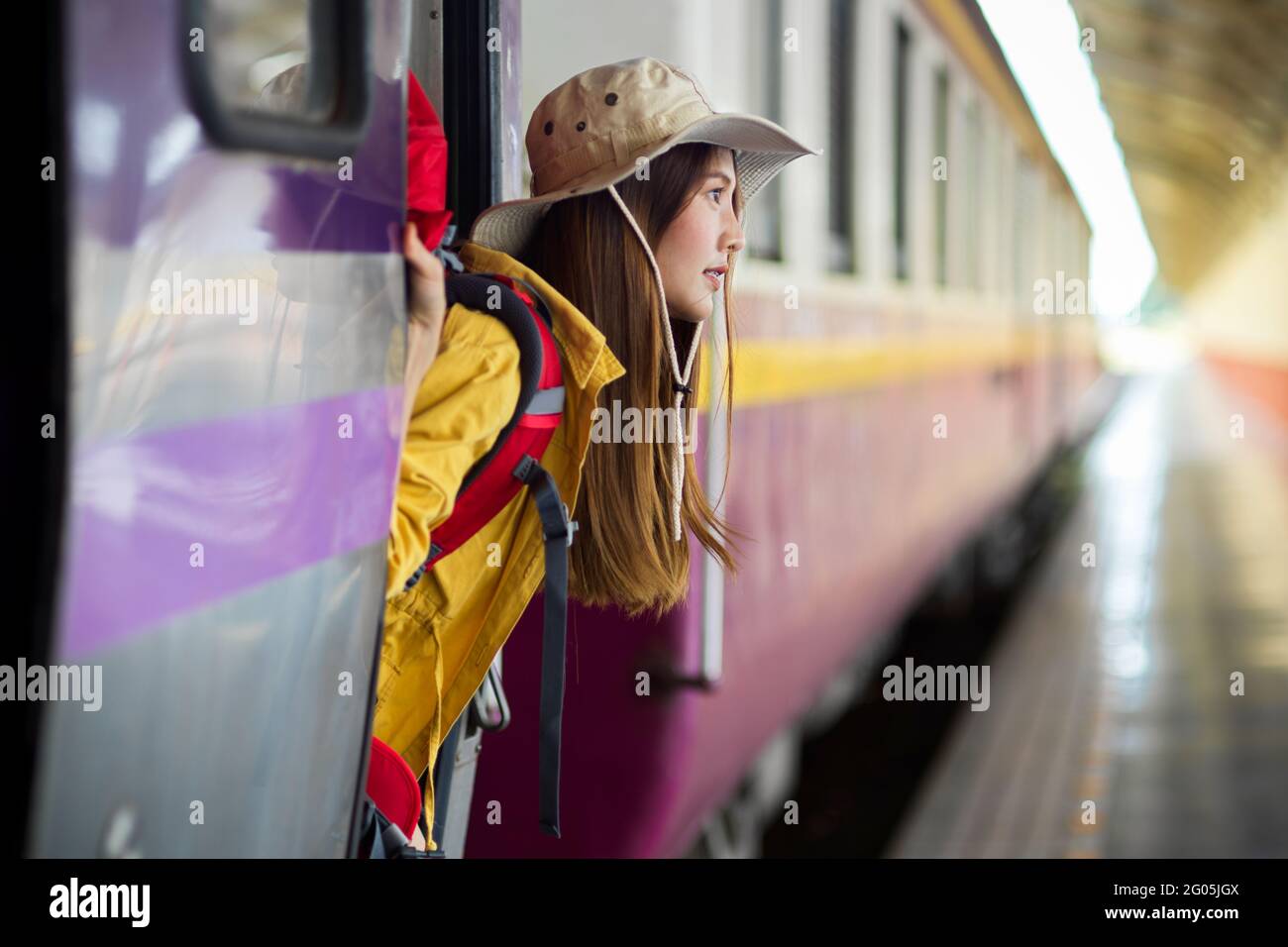 Vista laterale di una giovane donna zaino in spalla scendendo il treno, concetto di viaggio Foto Stock