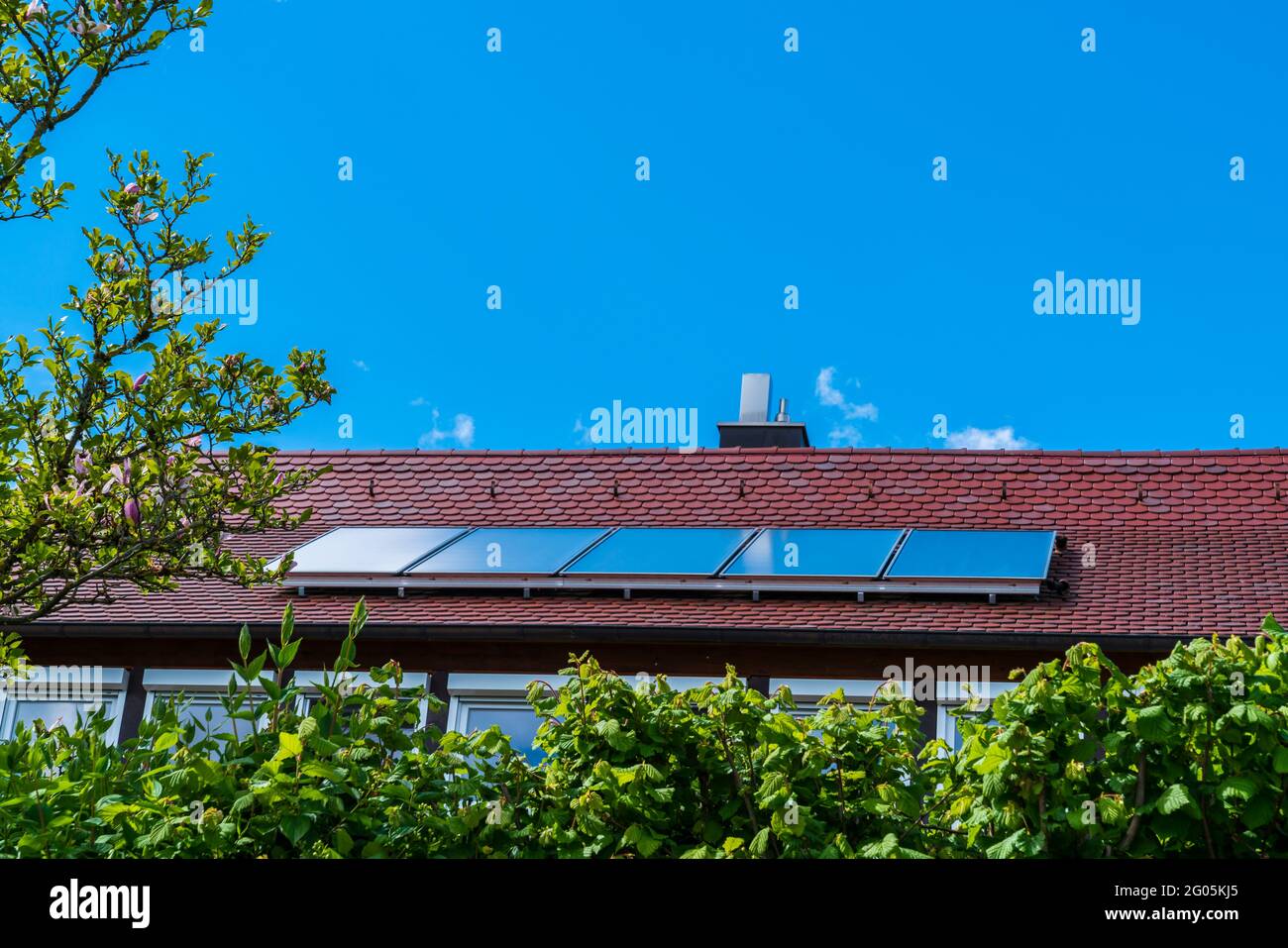 Pannelli solari sul tetto rosso di una casa che genera ambiente energia amichevole per l'edificio per salvare il pianeta Foto Stock