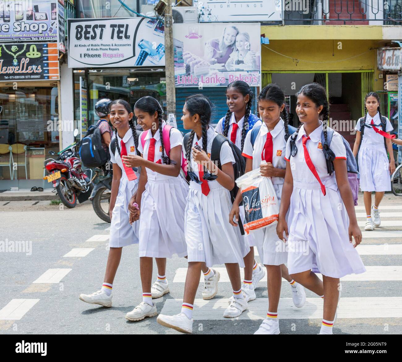 Studentesse srilankesi in scuola bianca uniforme croce zebra traversata dopo la scuola, Weligama, provincia meridionale, Sri lanka Foto Stock