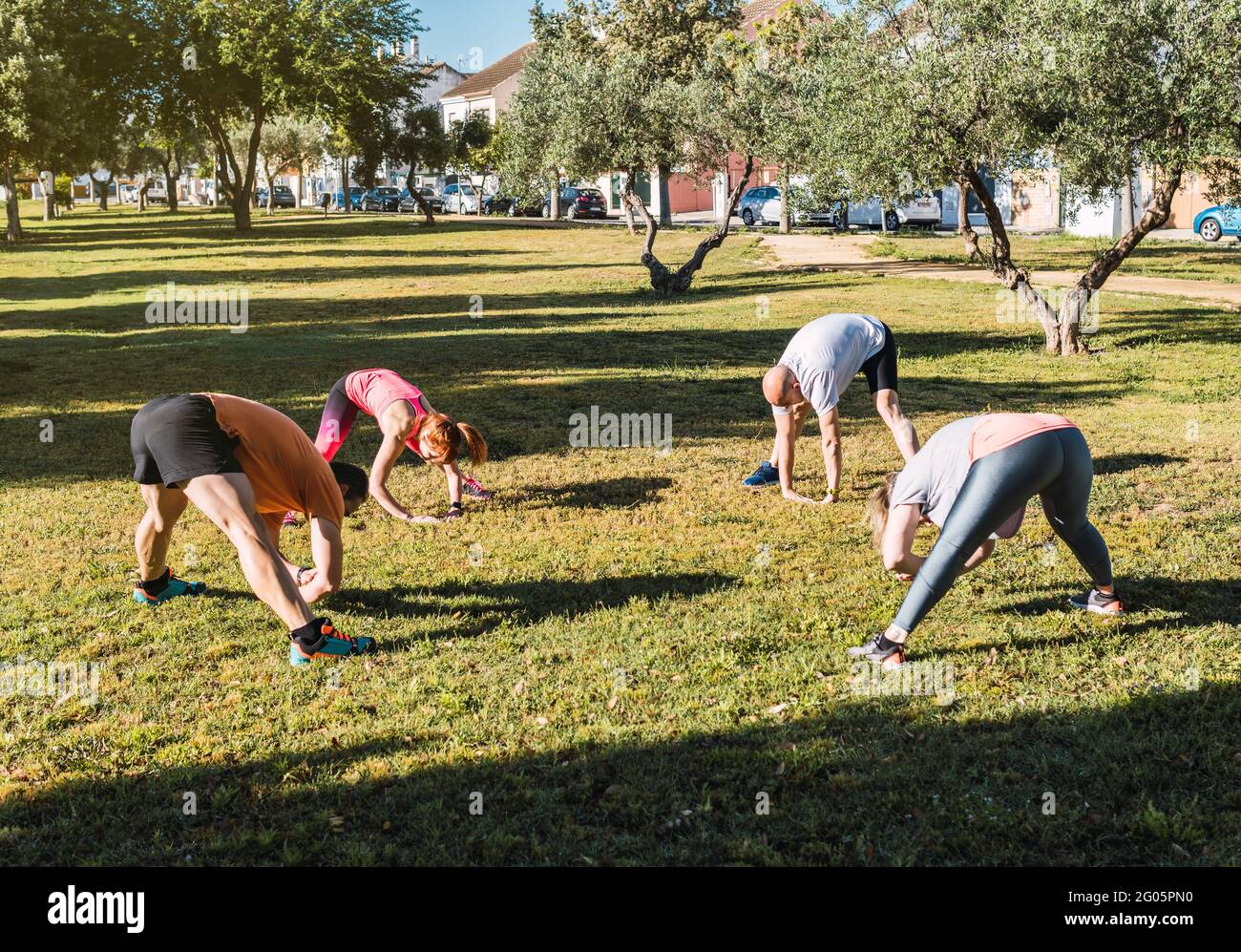Un gruppo di persone che si stendono le spalle in una sessione di formazione privata in un parco urbano Foto Stock
