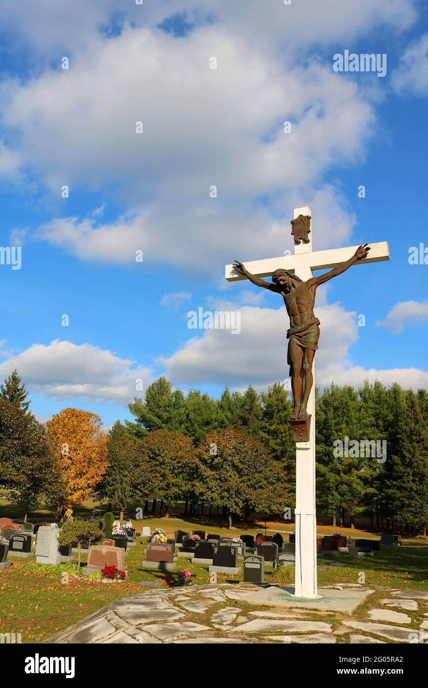 Immagine verticale di una statua di Gesù Cristo sulla croce in un cimitero su uno sfondo di cielo nuvoloso Foto Stock