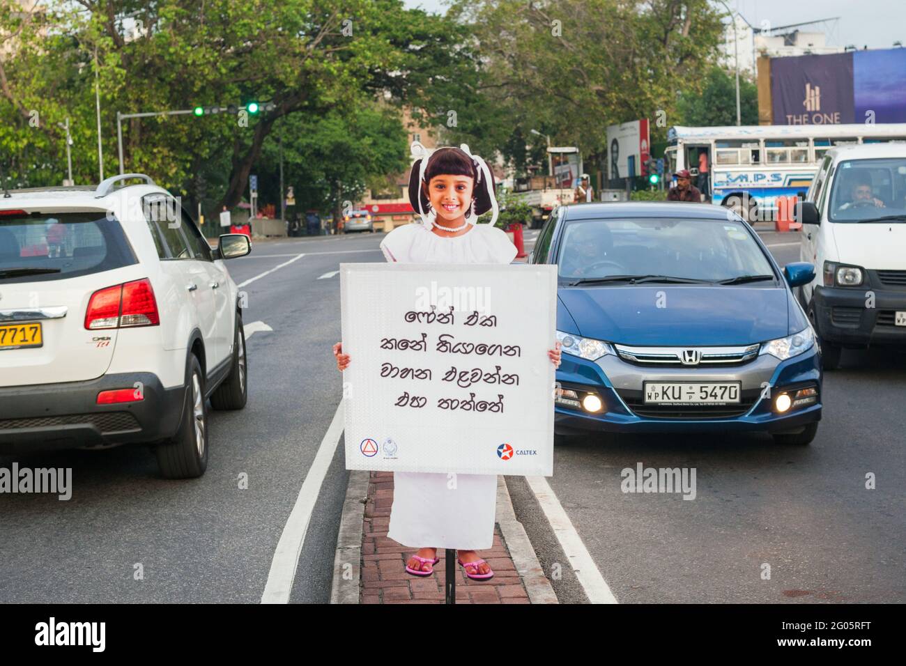 Taglio di cartone di bambino in possesso di avviso di sicurezza pubblica sulla guida di bevande su strada trafficata, Colombo, Sri Lanka Foto Stock