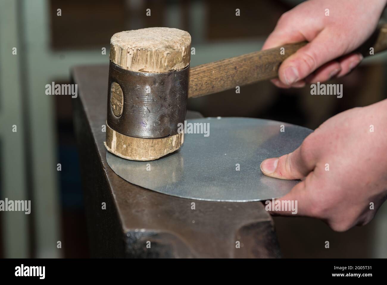 Il lavoratore esperto lavora con la lamiera del martello - lavorazione del metallo Foto Stock