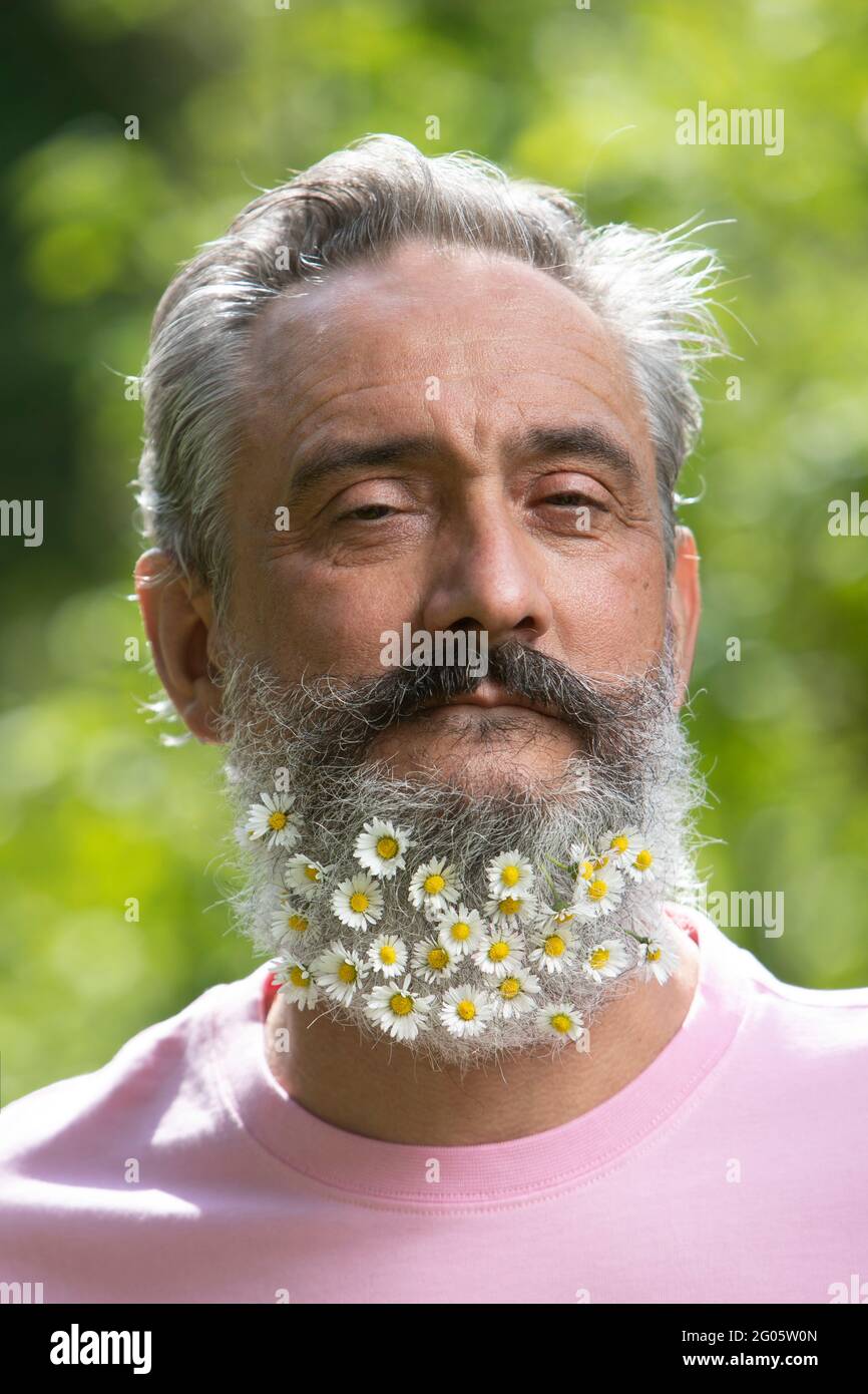 Ritratto creativo dell'uomo anziano con una barba decorata con fiori Foto Stock