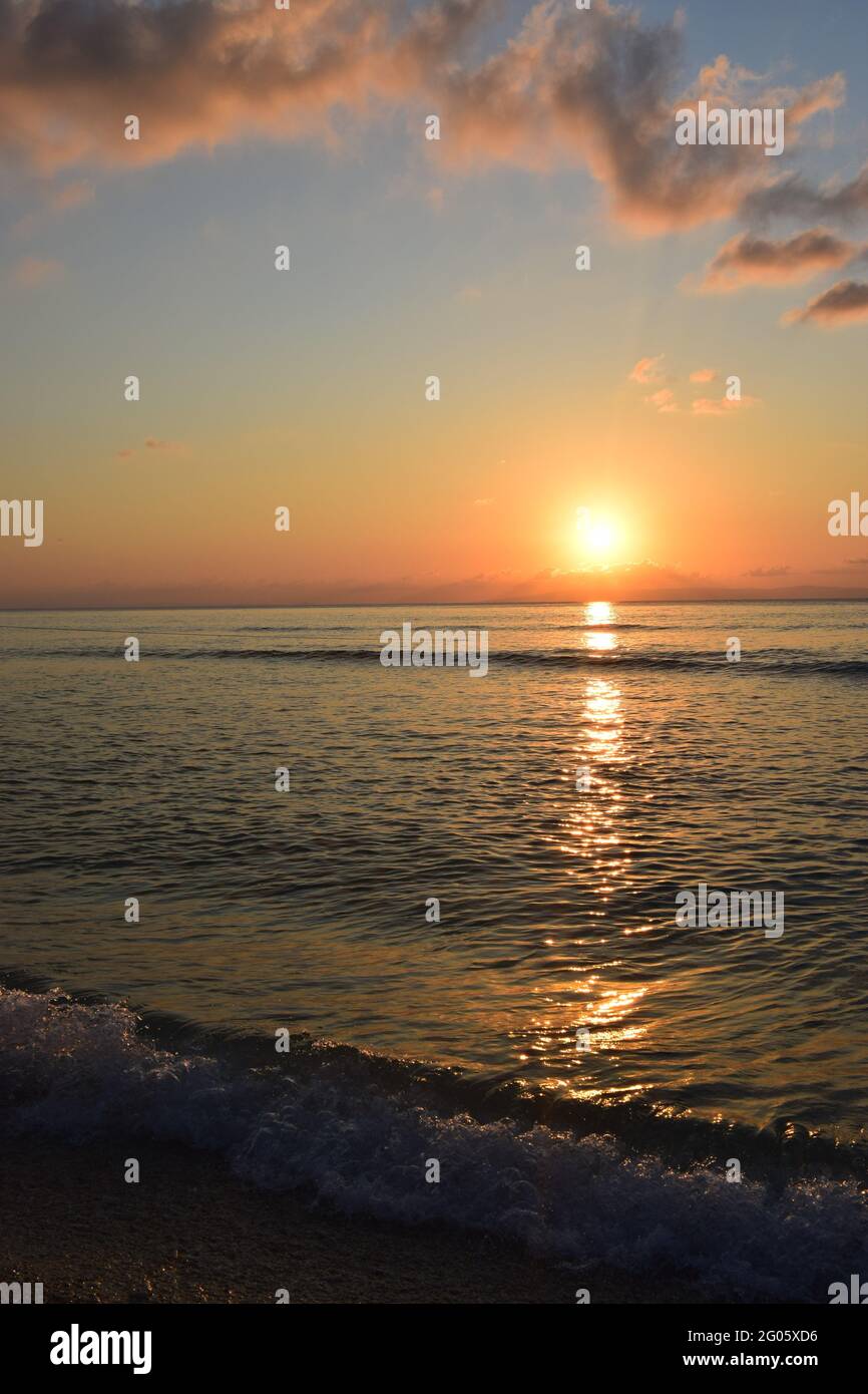 Riflesso d'oro del tramonto sulla riva di un oceano calmo Foto Stock