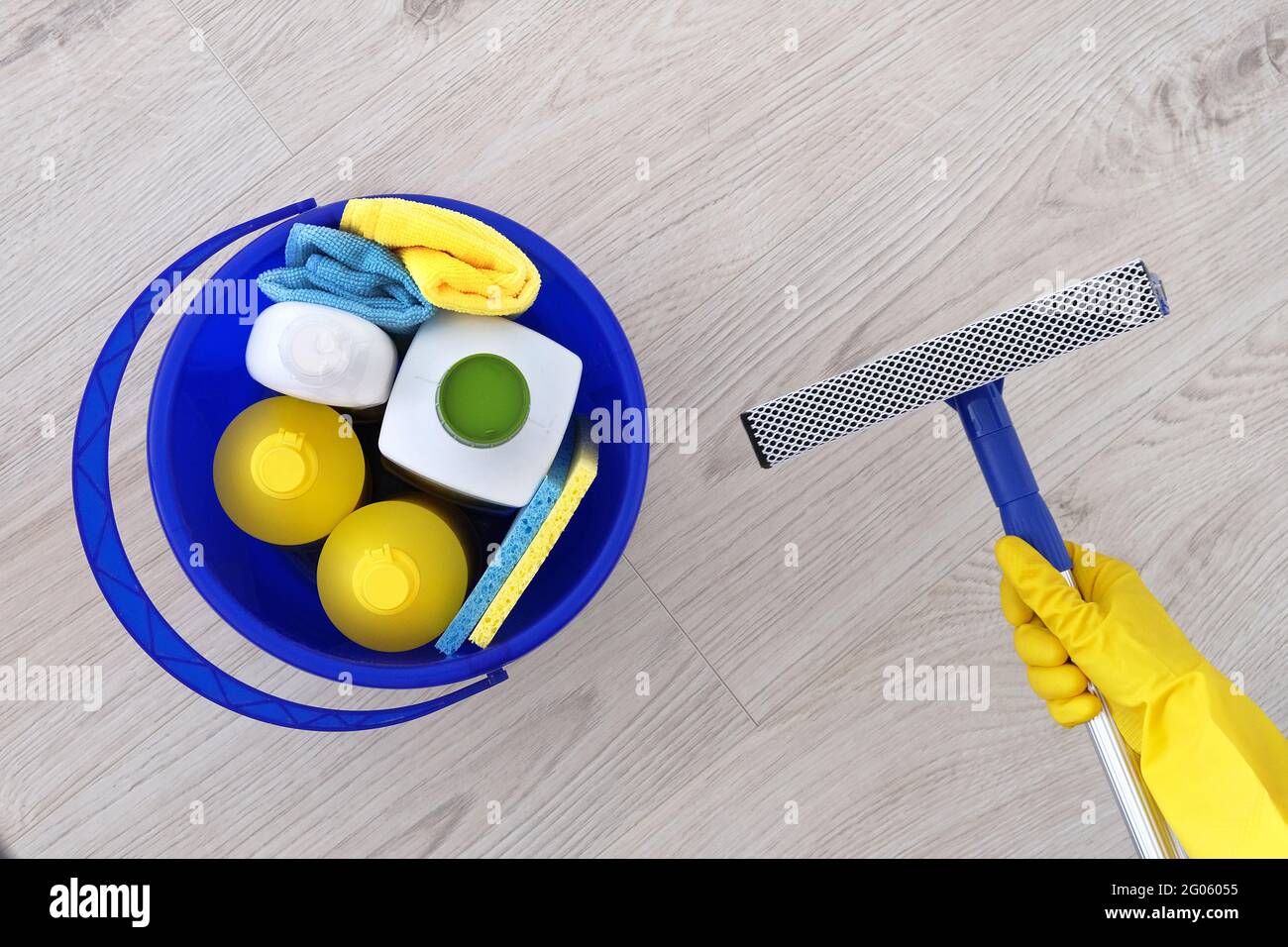Detergenti in bottiglie di plastica, spugne in secchio blu per uso domestico. Mop per lavare le finestre in mano in guanto di gomma giallo Сleaning accessori. Disposizione piatta Foto Stock